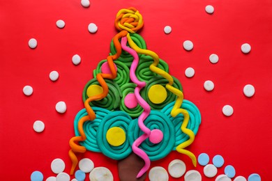 Plasticine Christmas tree and snow on red background, flat lay