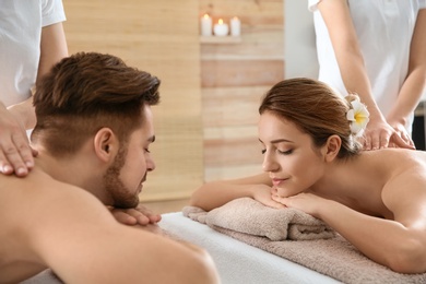 Photo of Romantic young couple enjoying back massage in spa salon