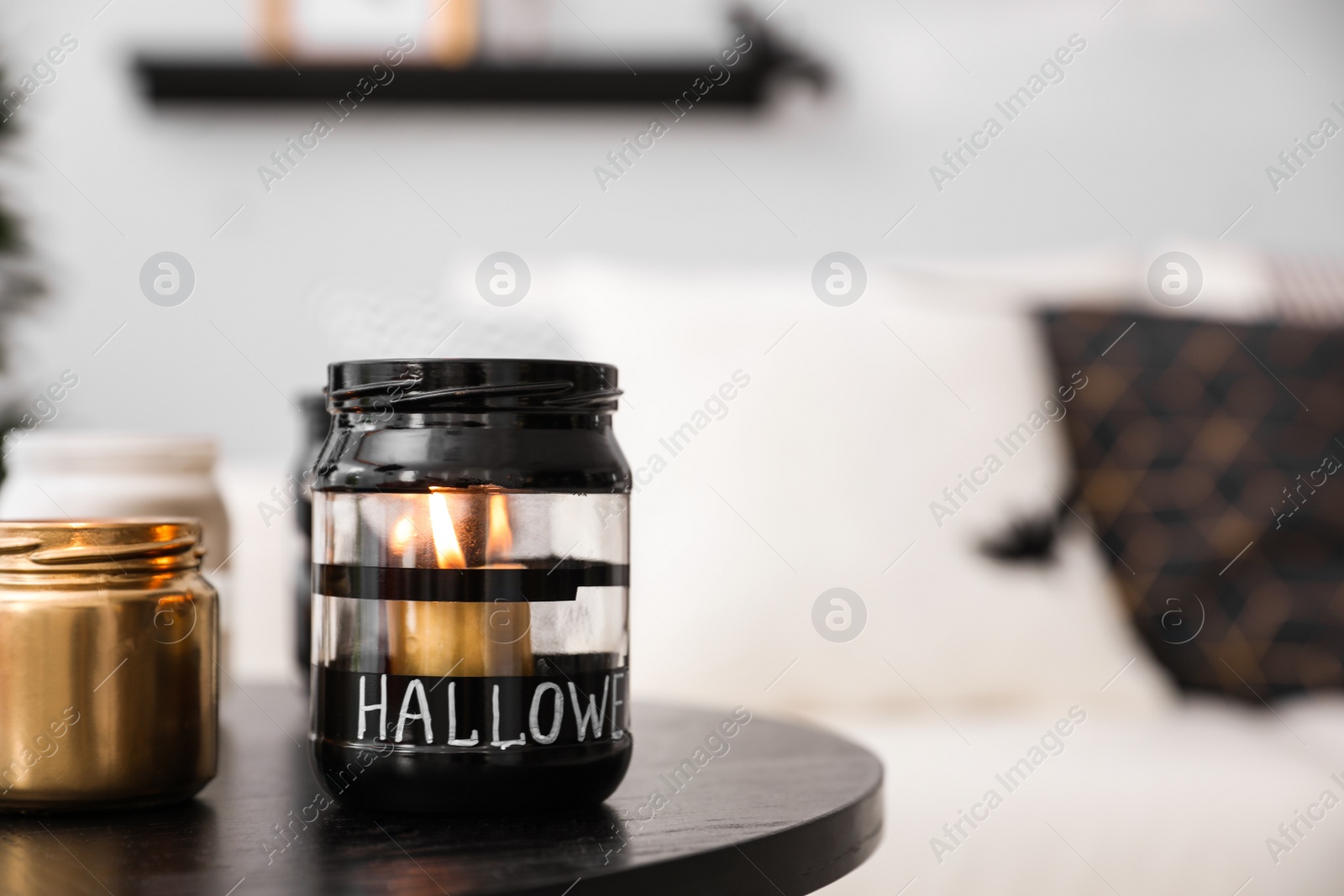 Photo of Burning candles on table in room. Idea for Halloween interior