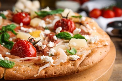 Pita pizza with prosciutto, pineapple, grilled tomatoes and egg on wooden tray, closeup