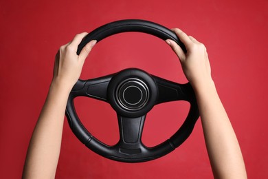 Photo of Woman holding steering wheel on red background, closeup