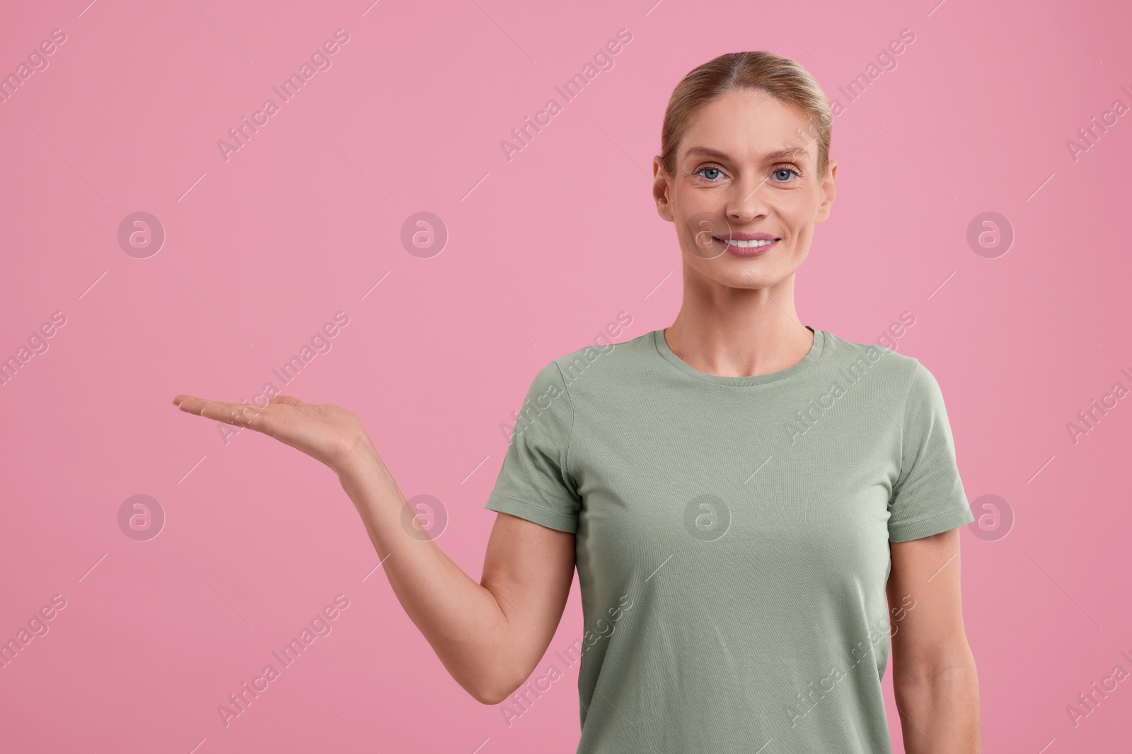 Photo of Special promotion. Smiling woman holding something on pink background. Space for text