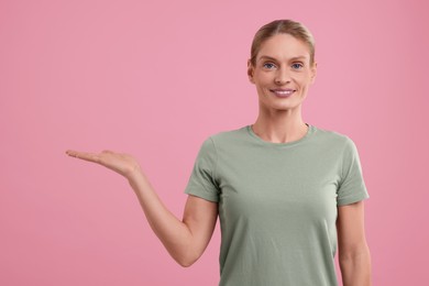 Special promotion. Smiling woman holding something on pink background. Space for text