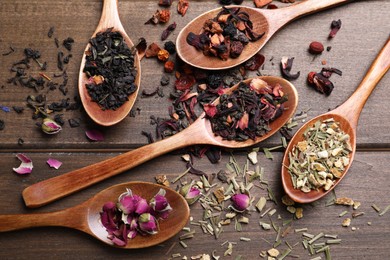 Flat lay composition with different teas and spoons on wooden table