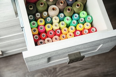 Colorful sewing threads in open drawer