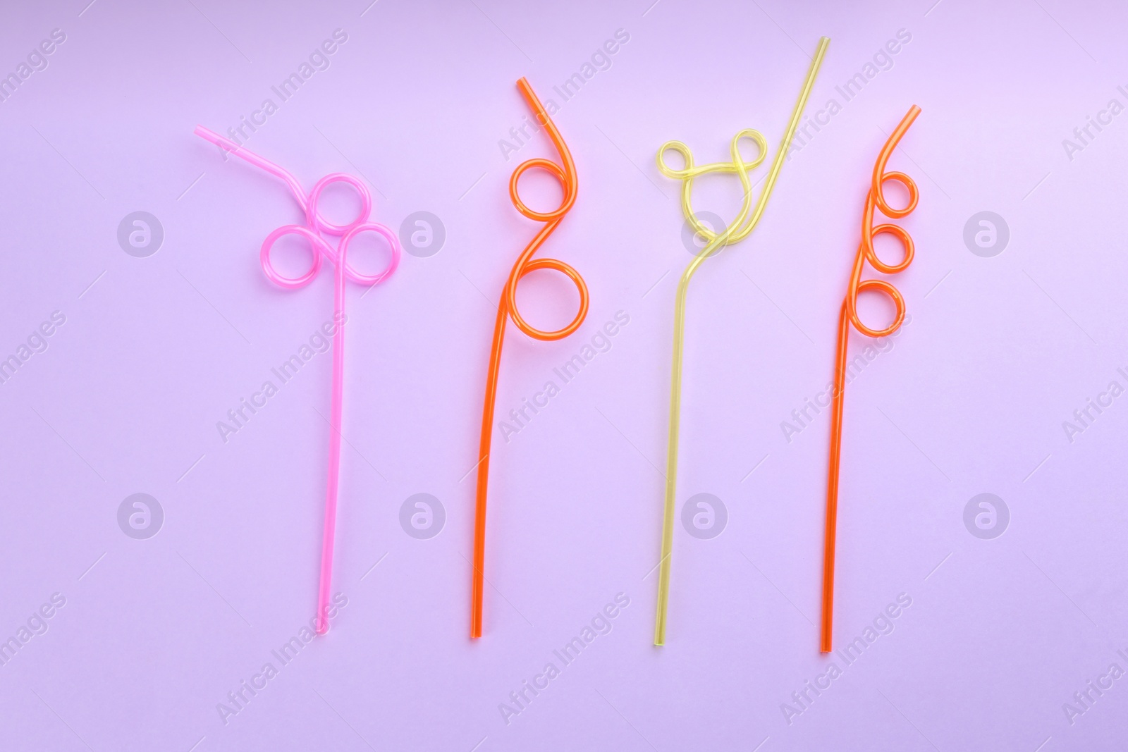 Photo of Colorful plastic drinking straws on violet background, flat lay