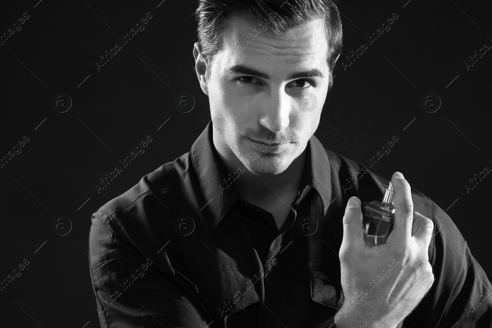 Photo of Handsome young man using perfume, black and white effect