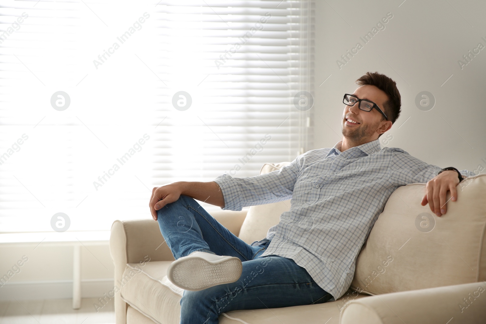 Photo of Young man relaxing on couch near window at home