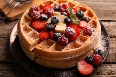 Tasty Belgian waffles with fresh berries, cheese and powdered sugar on wooden table, closeup