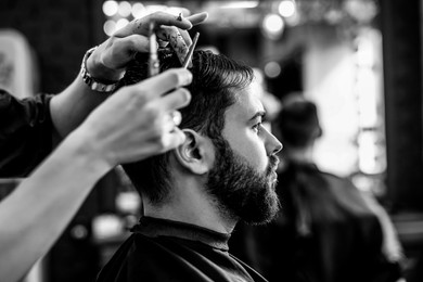 Image of Professional hairdresser working with client in barbershop. Black and white effect