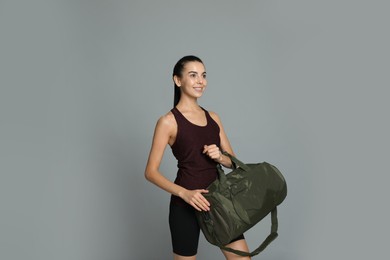 Beautiful woman with sports bag on grey background