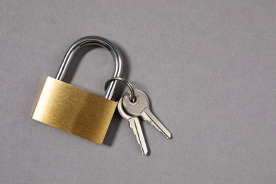 Steel padlock with keys on grey background, top view. Space for text