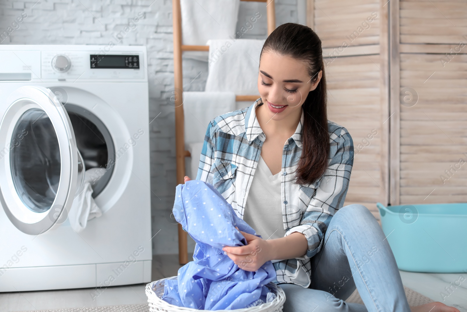 Photo of Young woman with laundry basket at home