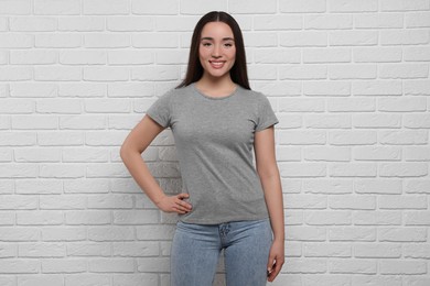 Photo of Woman wearing stylish gray T-shirt near white brick wall