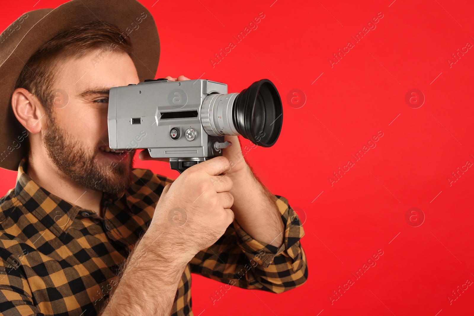 Photo of Young man with vintage video camera on red background