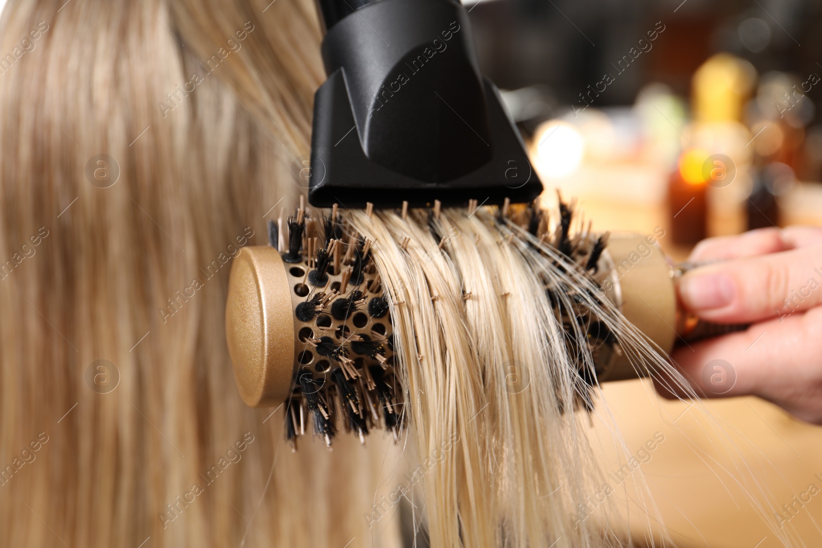 Photo of Hairdresser blow drying client's hair in salon, closeup