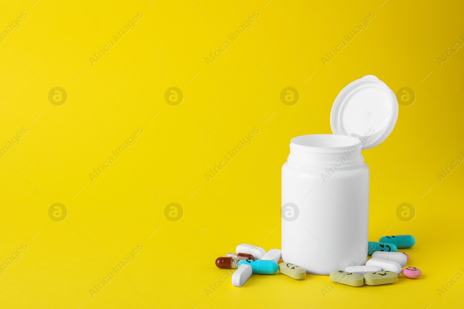 Photo of Different antidepressants with happy emoticons and medical jar on yellow background, space for text