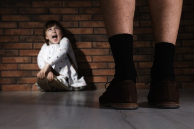 Photo of Adult man without pants standing in front of scared little girl indoors. Child in danger