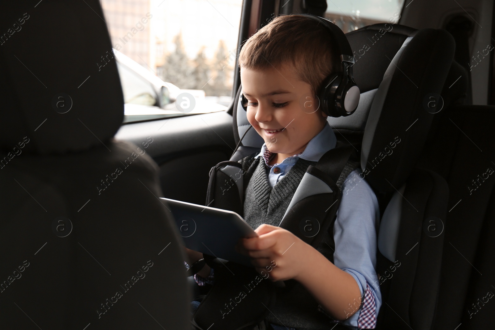 Photo of Cute little boy listening to audiobook in car