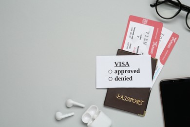 Flat lay composition with passport, tickets and earphones on light grey background, space for text. Visa receiving