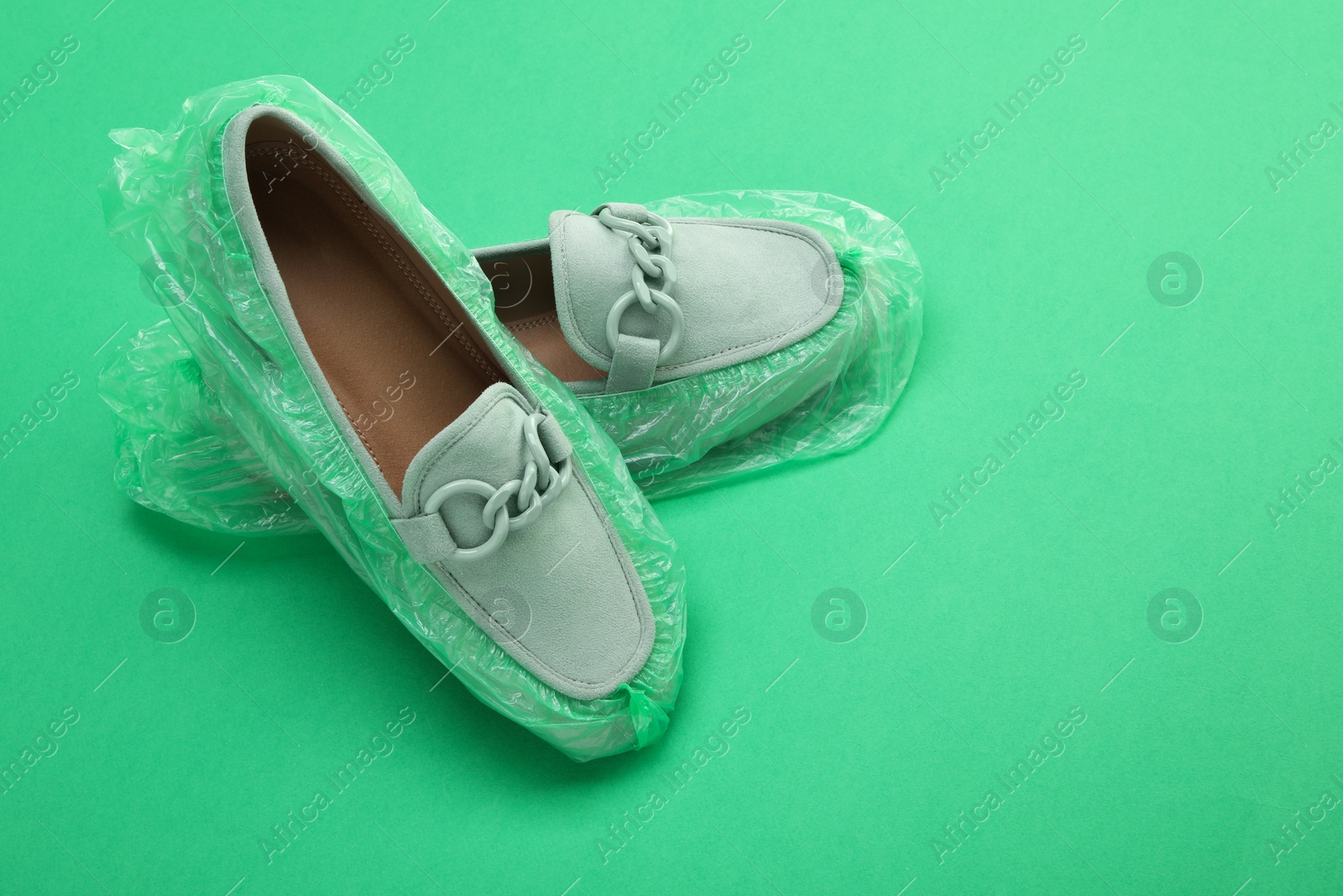 Photo of Women's mules in shoe covers on green background, closeup. Space for text