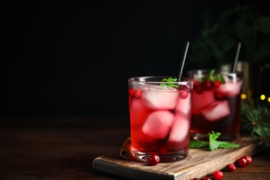 Photo of Tasty refreshing cranberry cocktail with mint on wooden table. Space for text