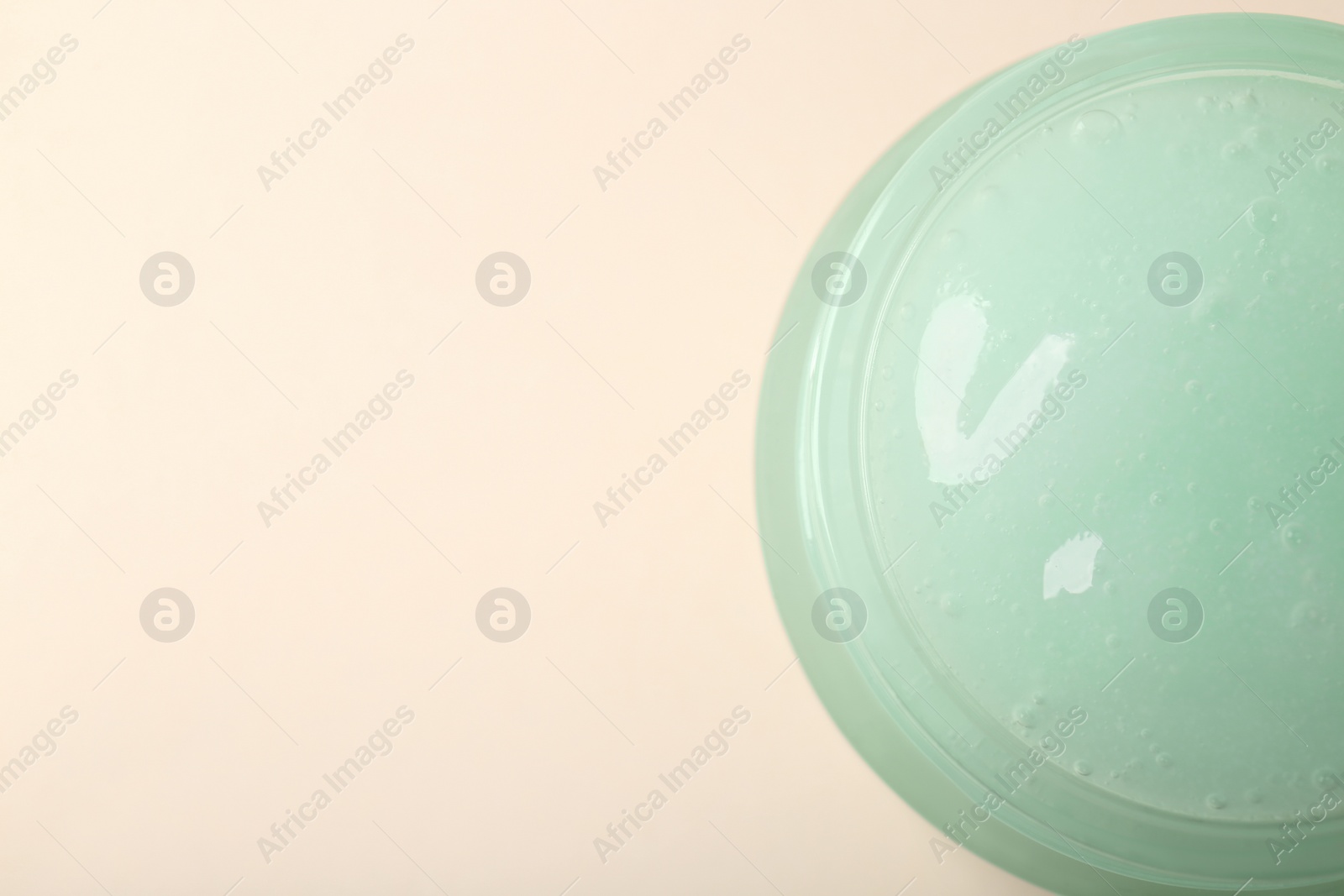 Photo of Jar of aloe gel on beige background, top view. Space for text