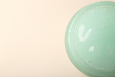 Photo of Jar of aloe gel on beige background, top view. Space for text