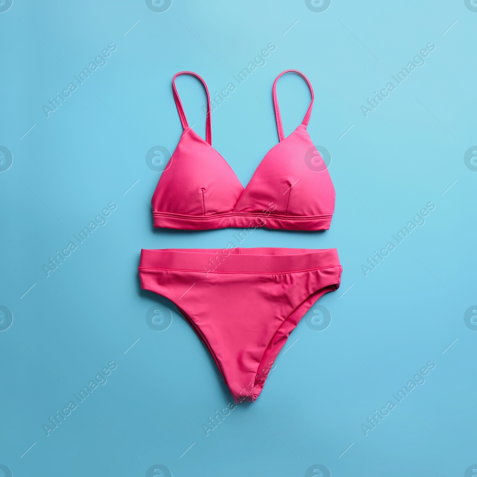 Photo of Beautiful pink bikini on light blue background, top view