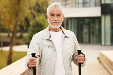 Photo of Senior man with Nordic walking poles outdoors