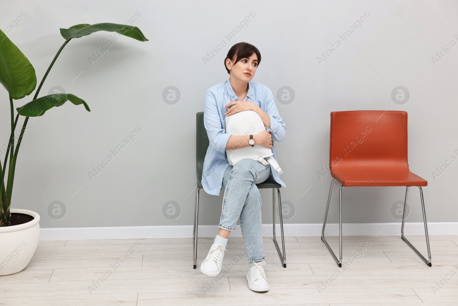 Photo of Woman sitting on chair and waiting for appointment indoors