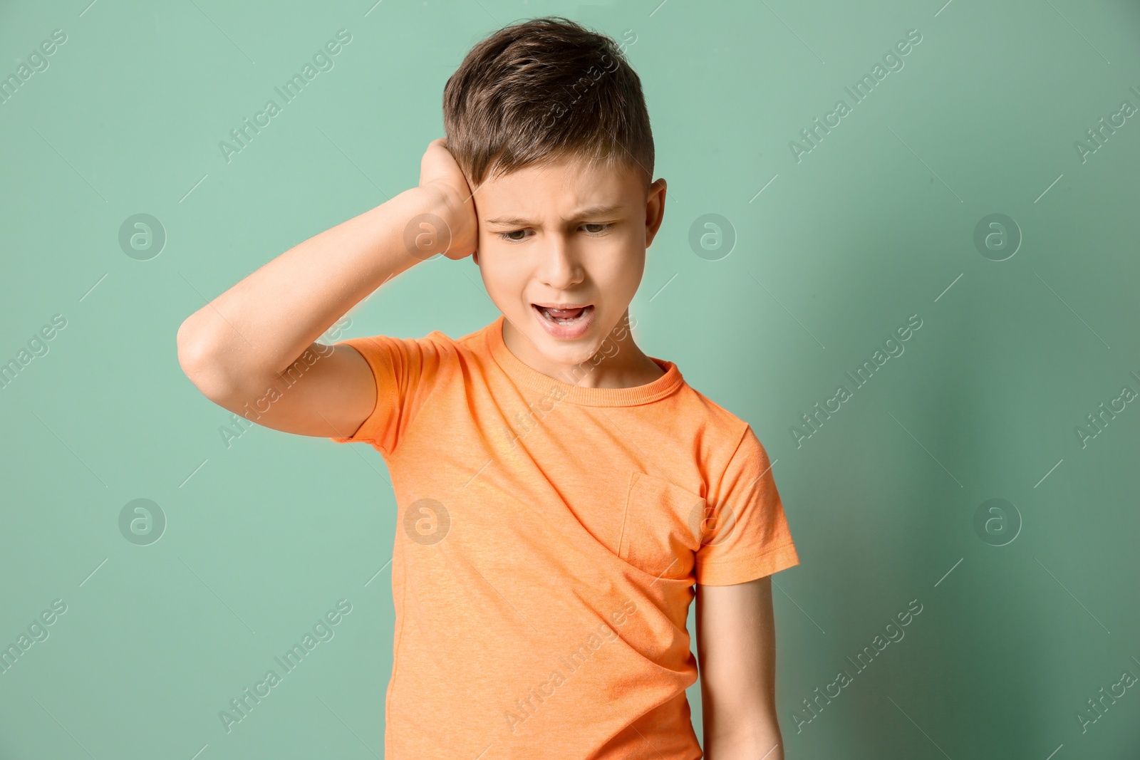 Photo of Little boy suffering from headache on color background