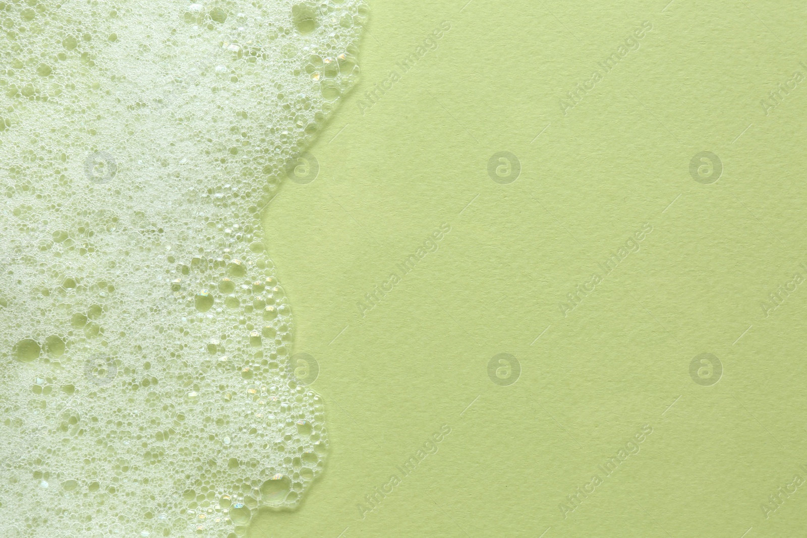 Photo of Fluffy bath foam on light green background, top view. Space for text