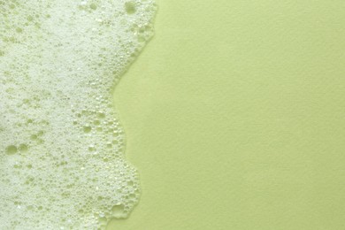 Photo of Fluffy bath foam on light green background, top view. Space for text