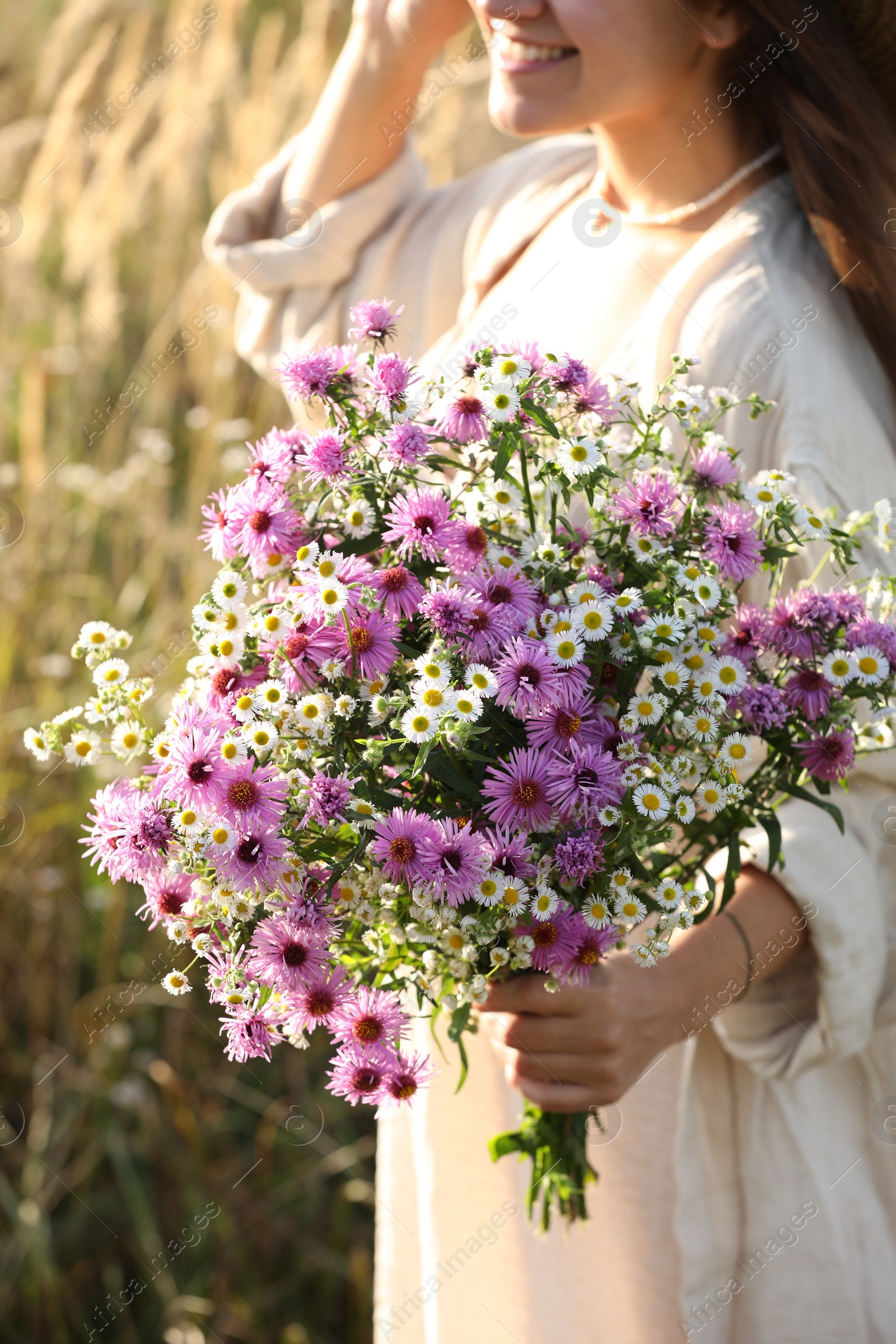 Photo of Woman holding bouquet of beautiful wild flowers outdoors, closeup