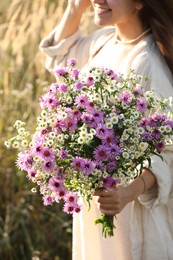 Photo of Woman holding bouquet of beautiful wild flowers outdoors, closeup