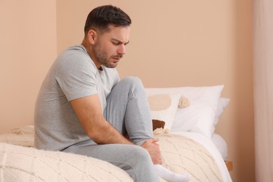 Photo of Man suffering from foot pain on bed indoors
