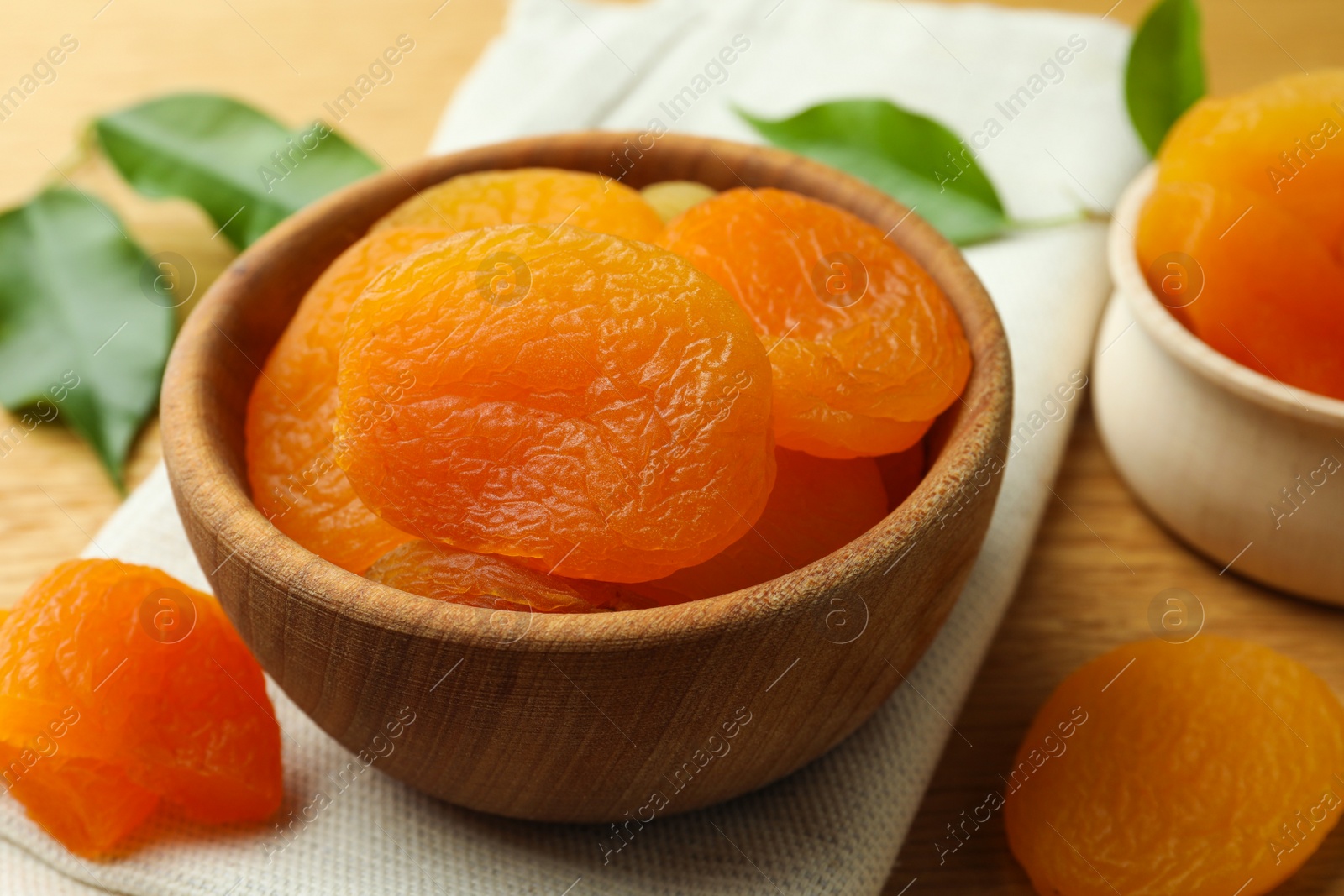 Photo of Bowl of tasty apricots on wooden table, closeup. Dried fruits