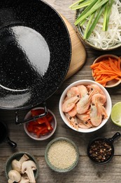 Photo of Flat lay composition with black wok, spices and products on wooden table