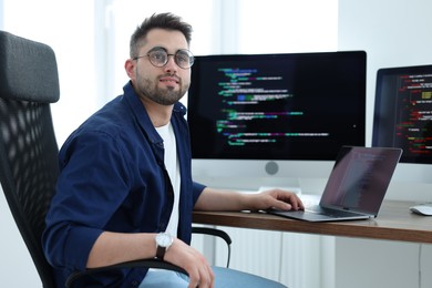 Photo of Young programmer working at desk in office