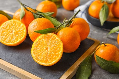 Board with ripe tangerines on table. Citrus fruit