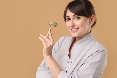 Photo of Cosmetologist with facial roller on beige background