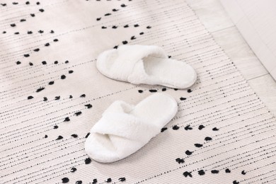 Photo of White soft slippers on carpet at home