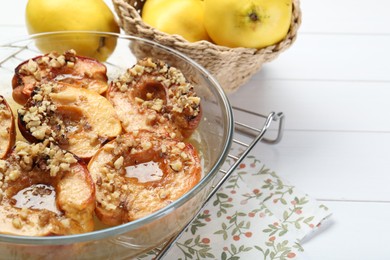 Photo of Delicious baked quinces with nuts in bowl and fresh fruits on white wooden table, closeup
