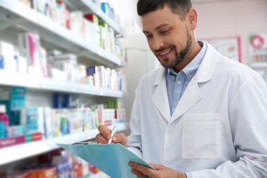 Professional pharmacist near shelves with merchandise in modern drugstore