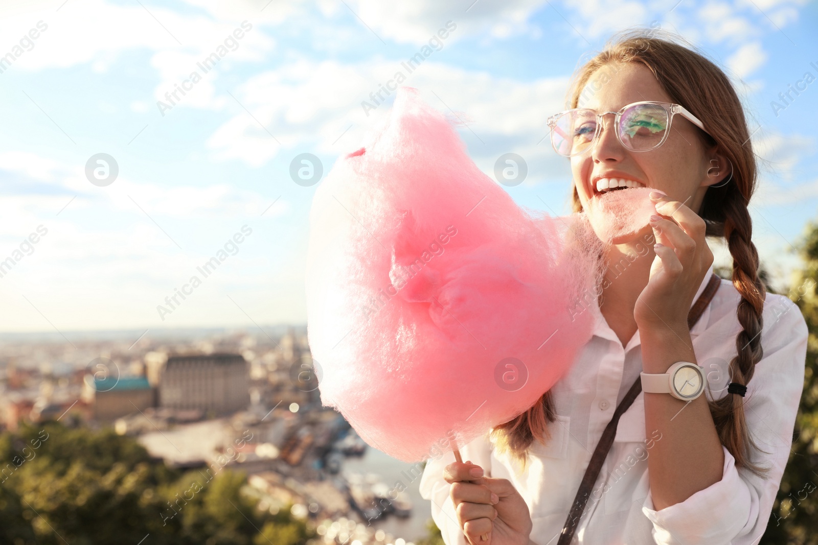 Photo of Young woman with cotton candy outdoors on sunny day. Space for text