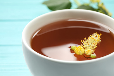 Cup of tea with linden blossom on table, closeup