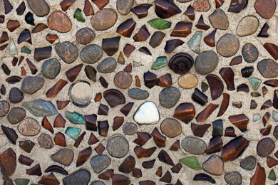 Texture of stone wall with rocks and glass pieces as background, closeup