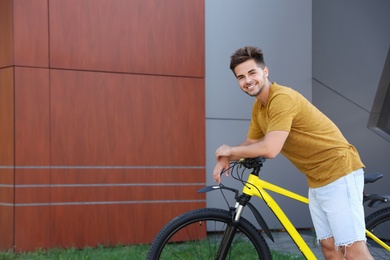Photo of Handsome young man with bicycle on city street. Space for text