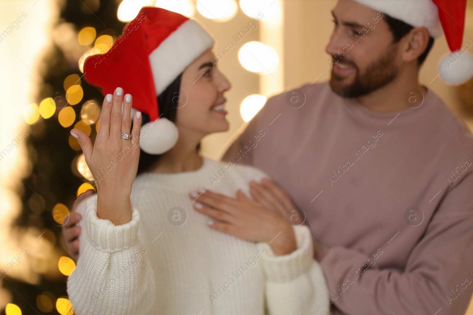 Photo of Making proposal. Happy woman with engagement ring and her fiance at home on Christmas, selective focus